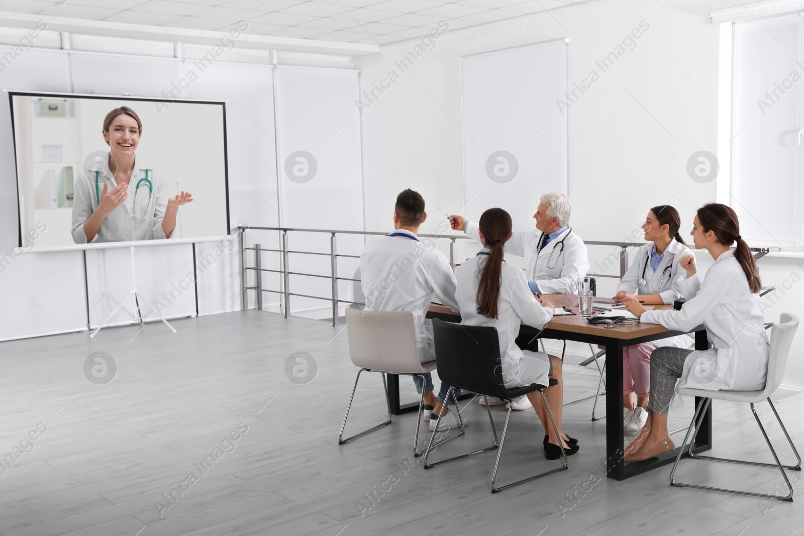 Team of doctors using video projector during conference indoors. Speaker on projection screen Image of Team of doctors using video projector during conference indoors. Speaker on projection screen