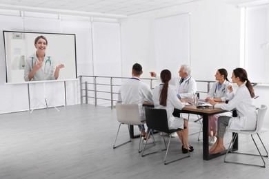 Image of Team of doctors using video projector during conference indoors. Speaker on projection screen