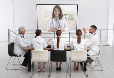 Image of Team of doctors using video projector during conference indoors. Speaker on projection screen
