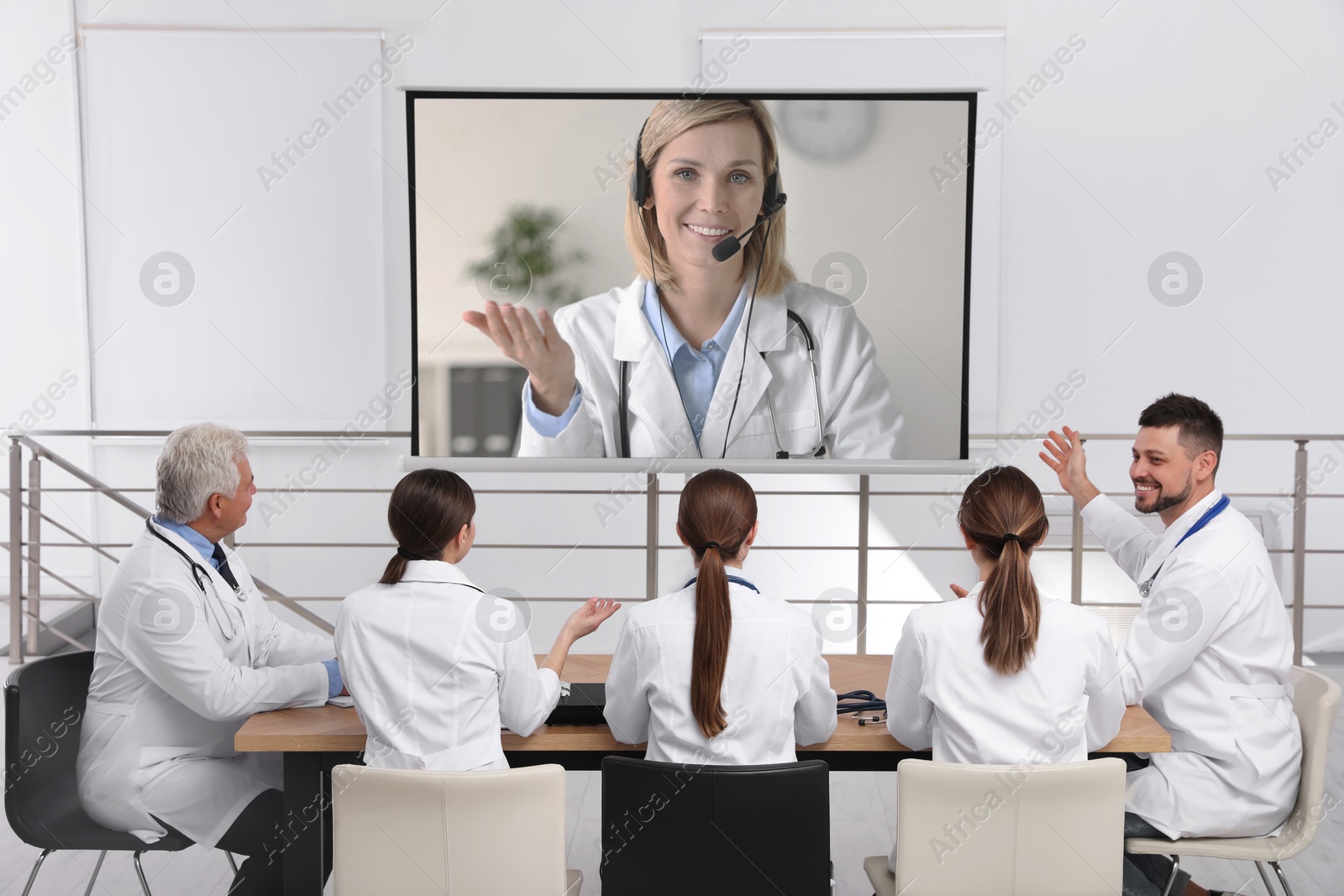Team of doctors using video projector during conference indoors. Speaker on projection screen Image of Team of doctors using video projector during conference indoors. Speaker on projection screen