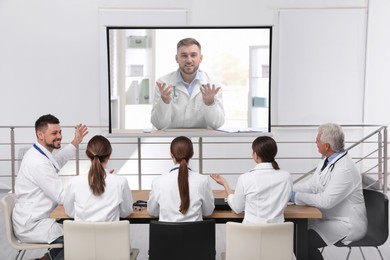 Image of Team of doctors using video projector during conference indoors. Speaker on projection screen