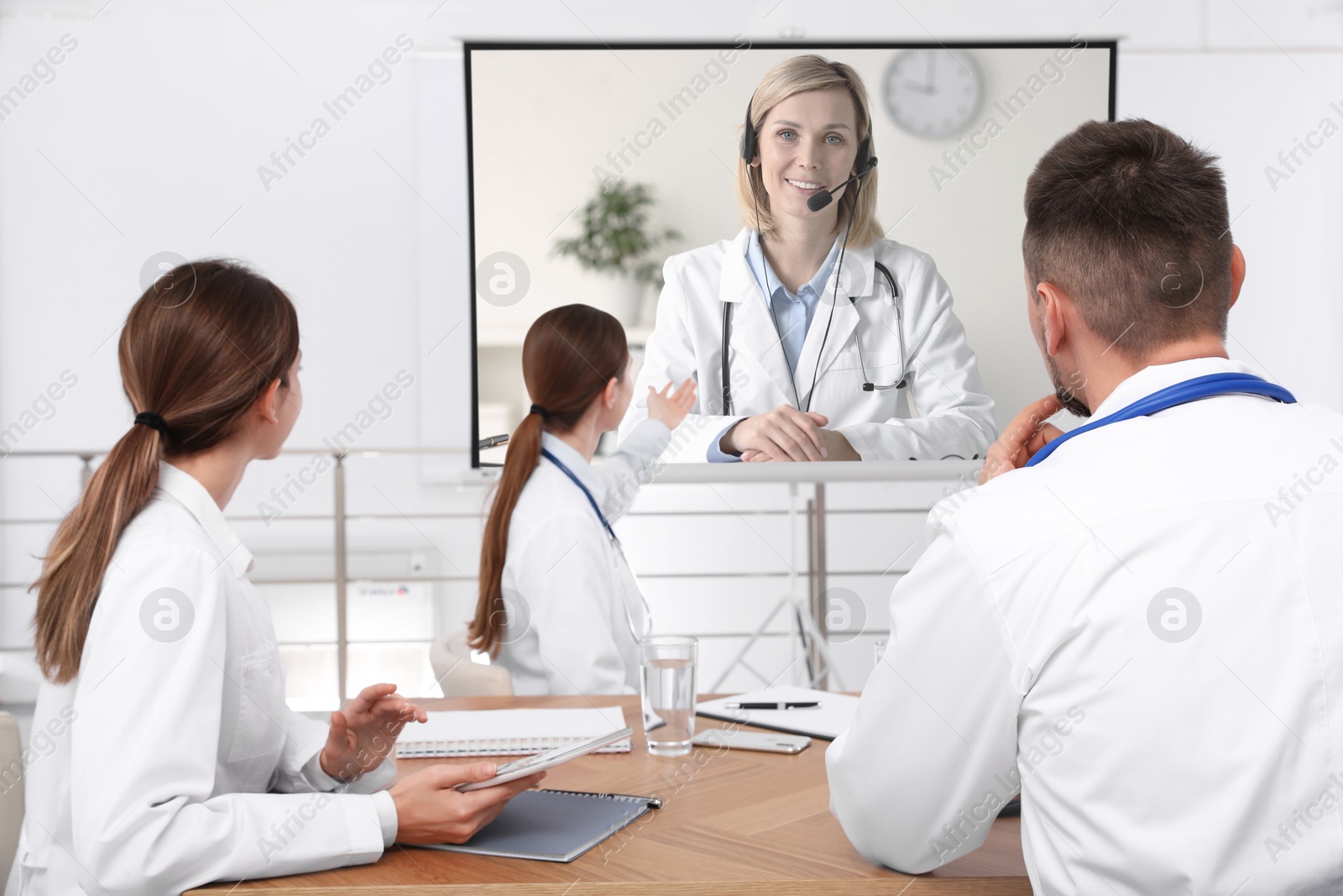 Team of doctors using video projector during conference indoors. Speaker on projection screen Image of Team of doctors using video projector during conference indoors. Speaker on projection screen