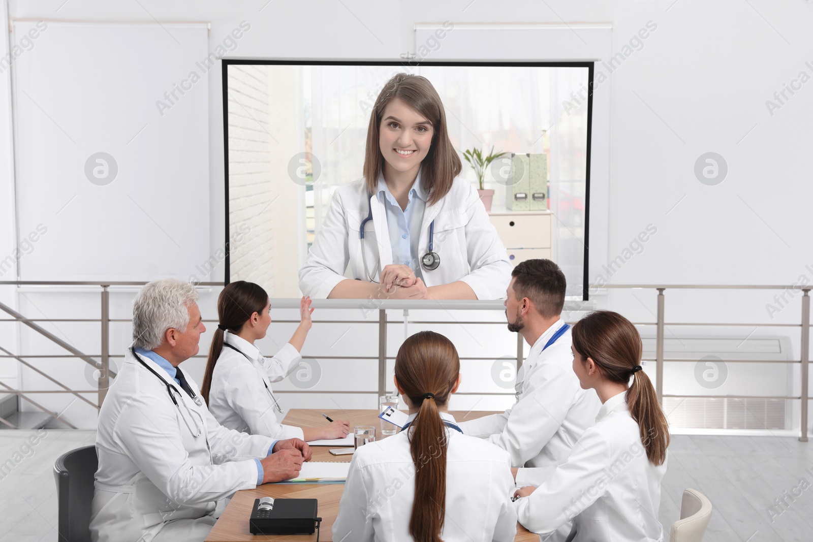 Team of doctors using video projector during conference indoors. Speaker on projection screen Image of Team of doctors using video projector during conference indoors. Speaker on projection screen