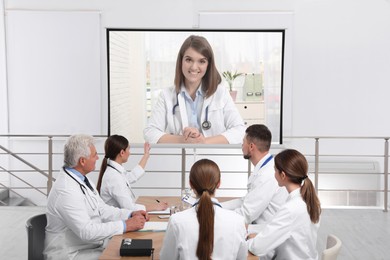 Image of Team of doctors using video projector during conference indoors. Speaker on projection screen