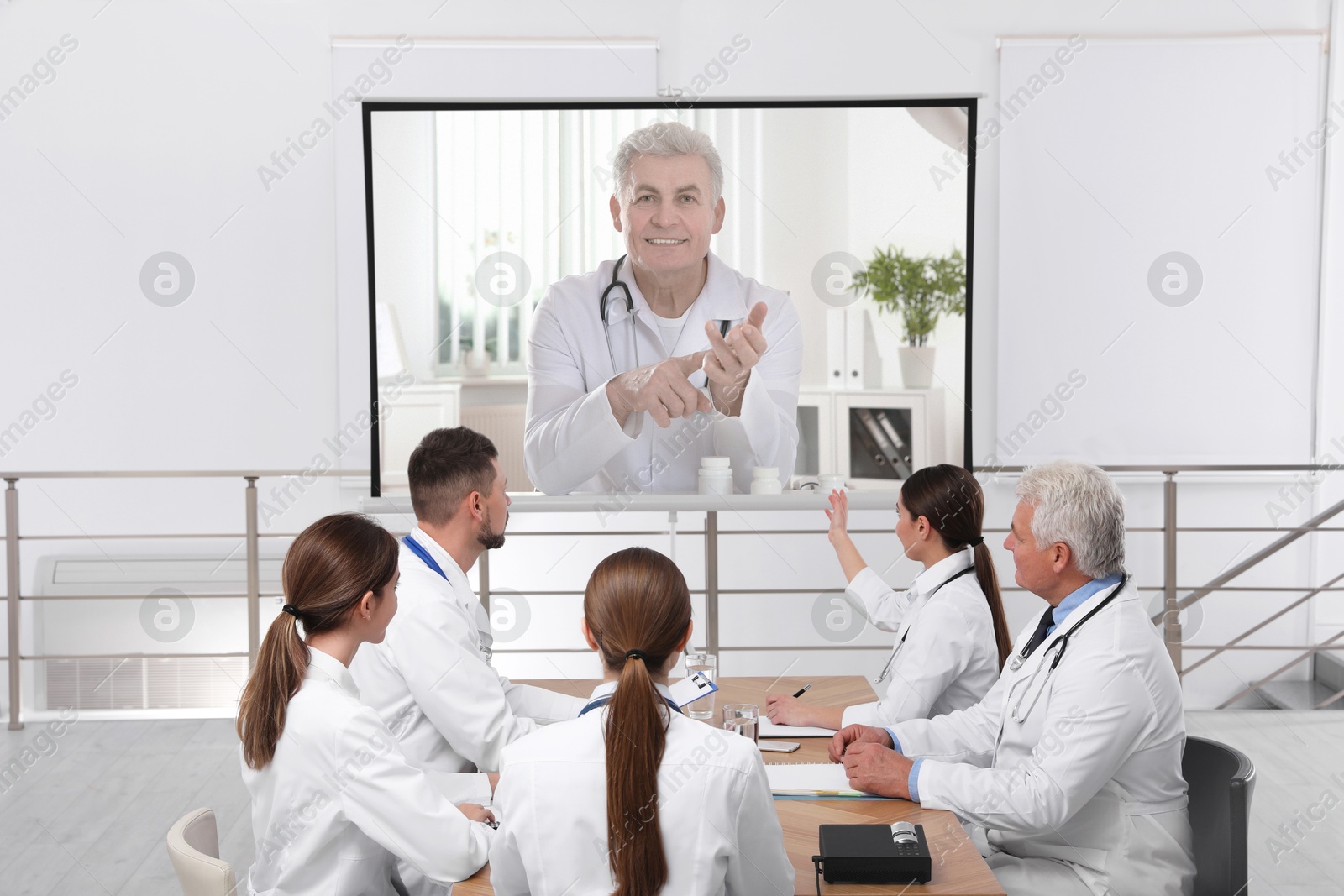 Team of doctors using video projector during conference indoors. Speaker on projection screen Image of Team of doctors using video projector during conference indoors. Speaker on projection screen