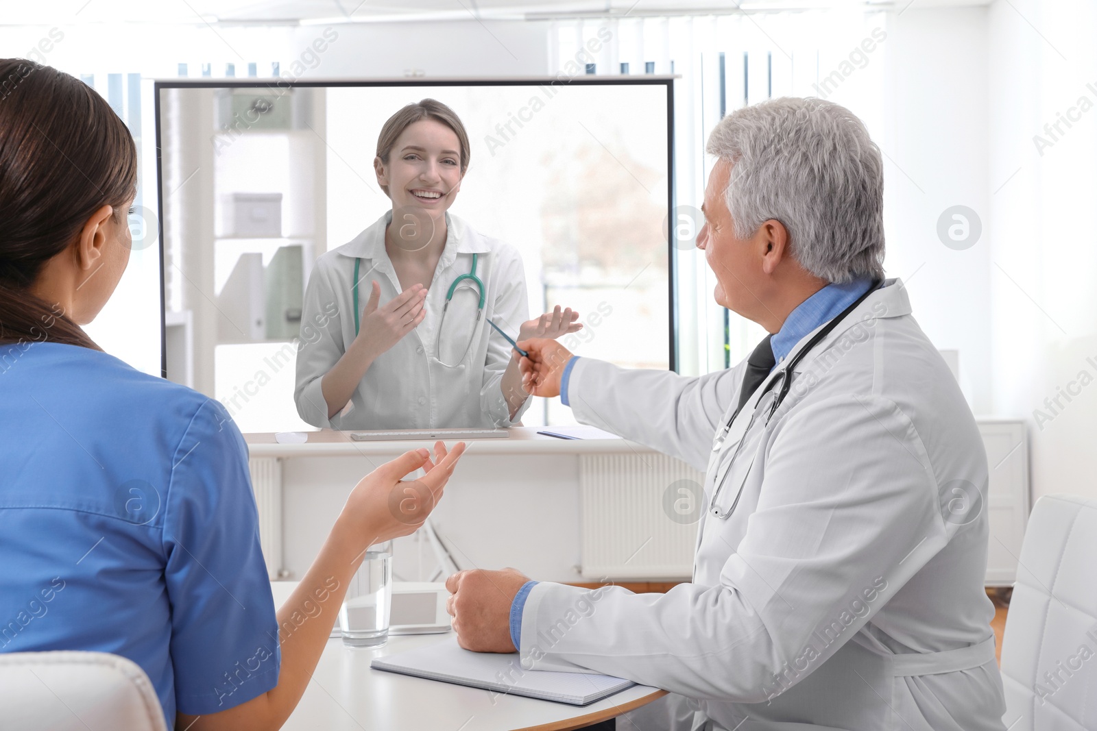 Doctors using video projector during conference indoors. Speaker on projection screen Image of Doctors using video projector during conference indoors. Speaker on projection screen