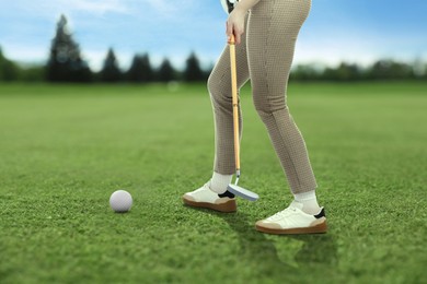 Image of Woman with club playing golf on green course, closeup