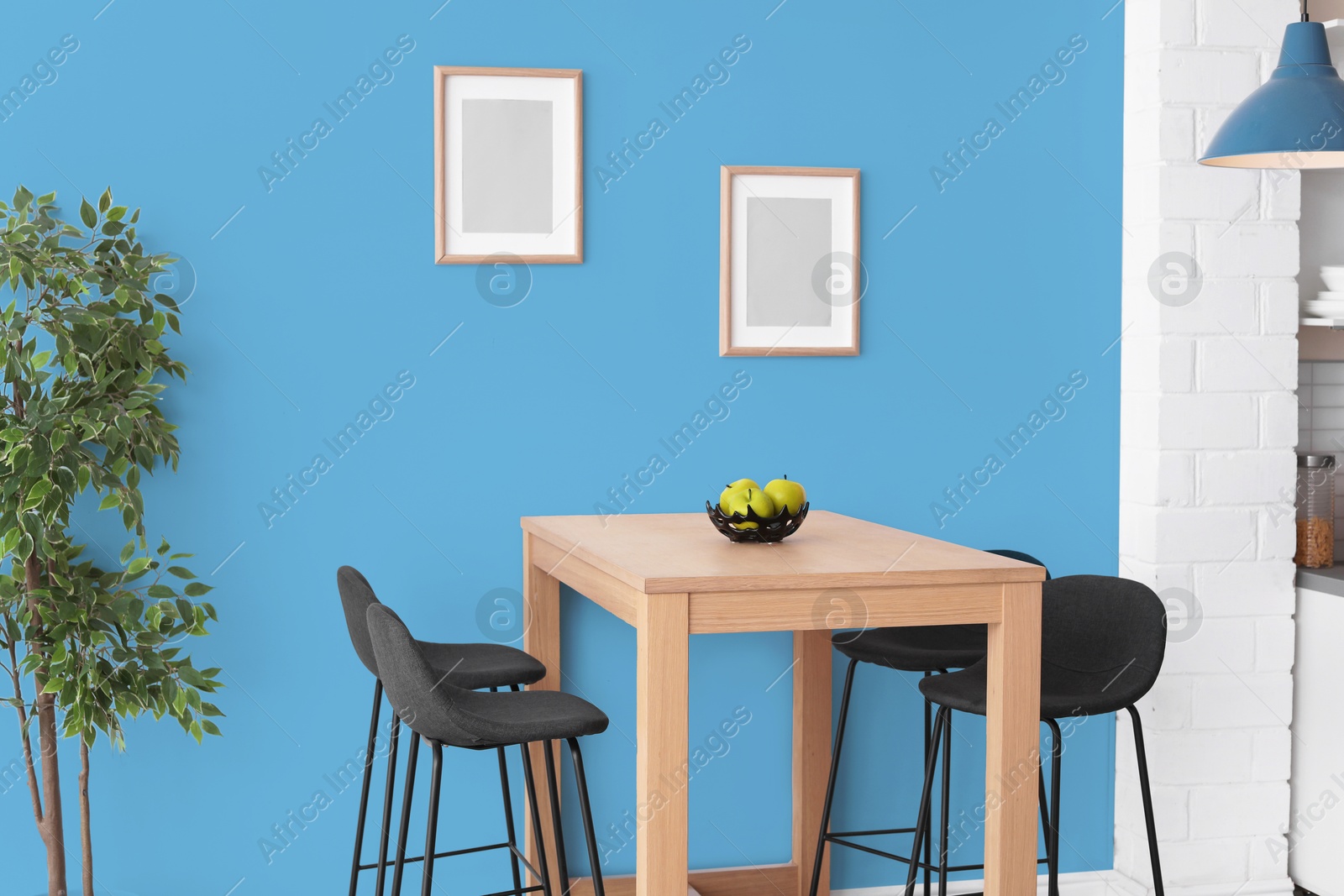 Dining table and chairs near light blue wall in room. Interior design Image of Dining table and chairs near light blue wall in room. Interior design