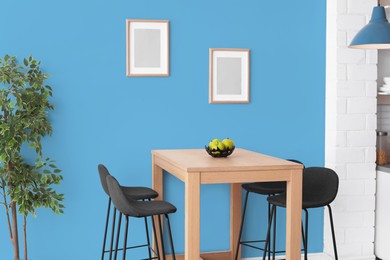 Image of Dining table and chairs near light blue wall in room. Interior design
