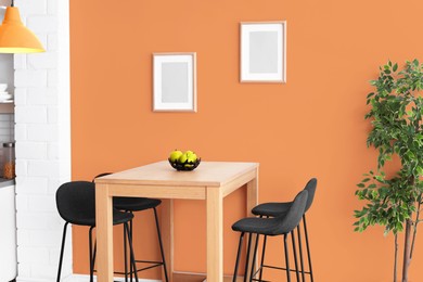 Image of Dining table and chairs near orange wall in room. Interior design