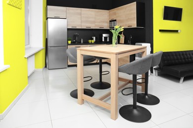 Image of Dining table with chairs in kitchen. Interior design with yellow and black walls