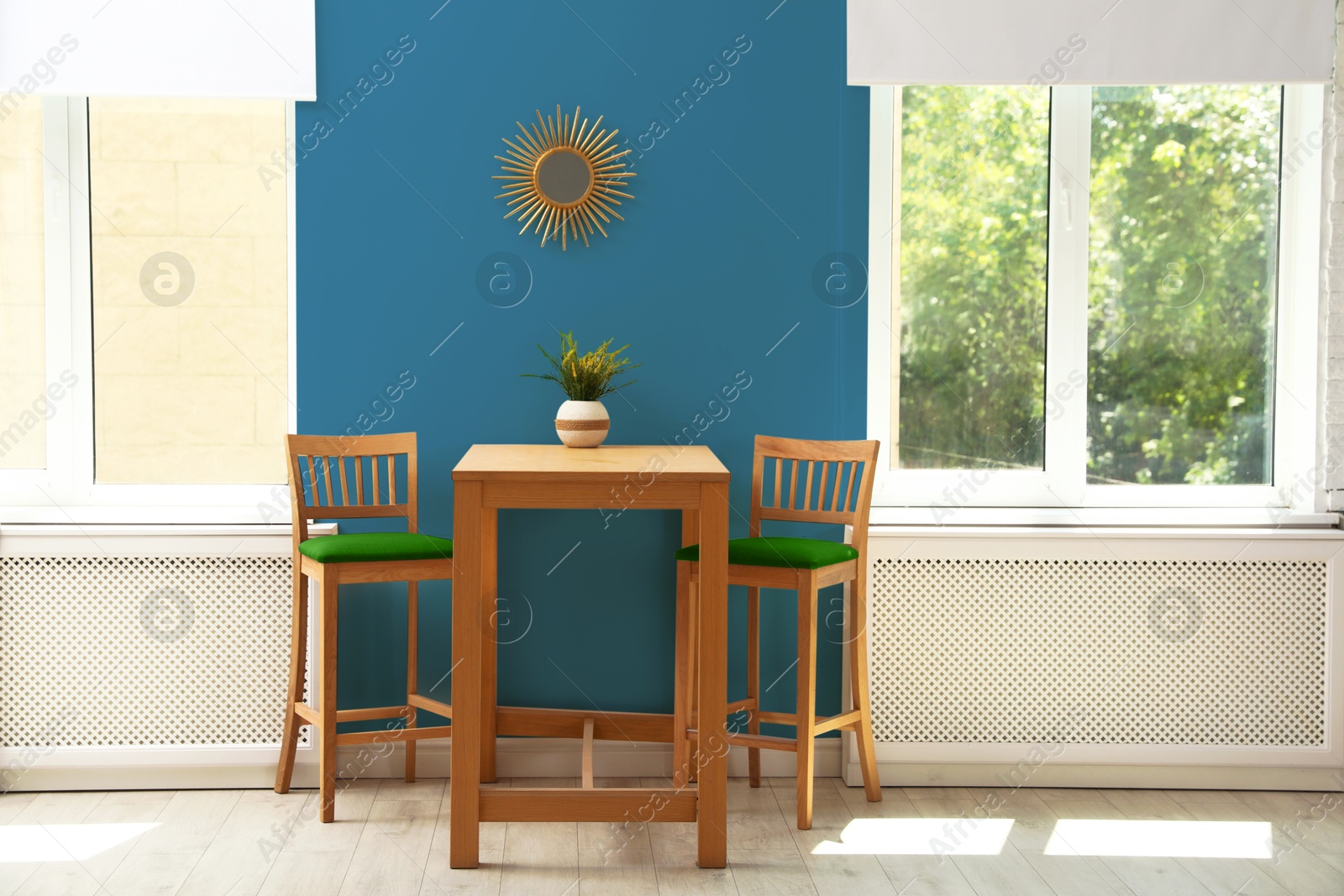 Dining table and chairs near blue wall and windows in room. Interior design Image of Dining table and chairs near blue wall and windows in room. Interior design