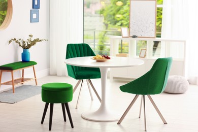 Image of White dining table and green chairs in room. Interior design