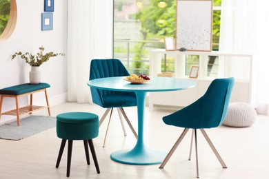 Image of Blue dining table and chairs in room. Interior design