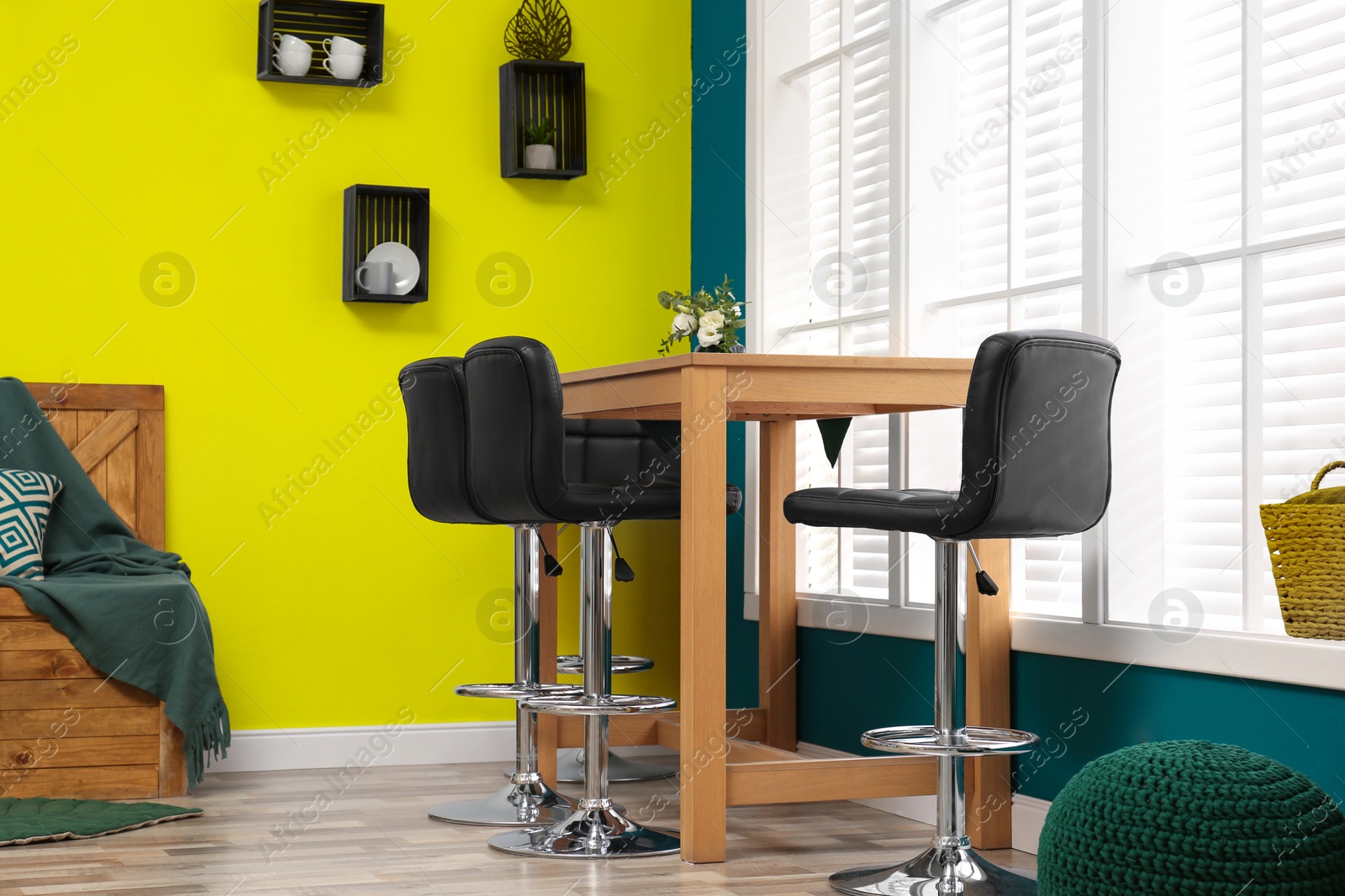 Image of Wooden dining table and chairs in room. Interior design with yellow and teal walls