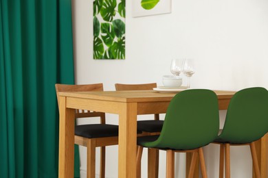 Image of Dining table and chairs in room. Interior design with green color accent
