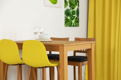 Image of Dining table and chairs in room. Interior design with yellow color accent