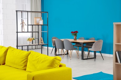 Image of Dining table and chairs near blue wall in room. Interior design