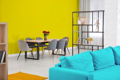 Image of Dining table and chairs near yellow wall in room. Interior design