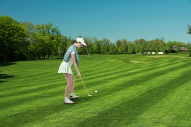 Image of Woman with club playing golf on green course