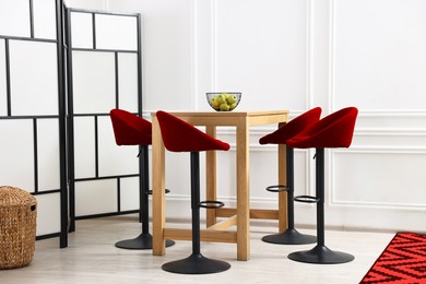 Image of Dining table and red chairs in room. Interior design