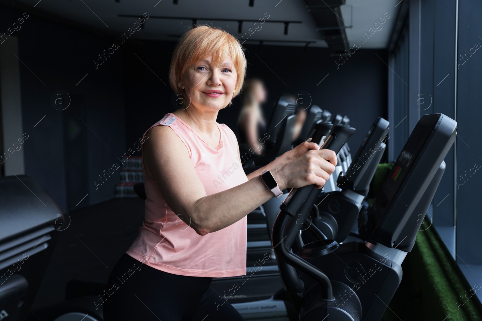 Senior woman training on elliptical machine in gym Photo of Senior woman training on elliptical machine in gym