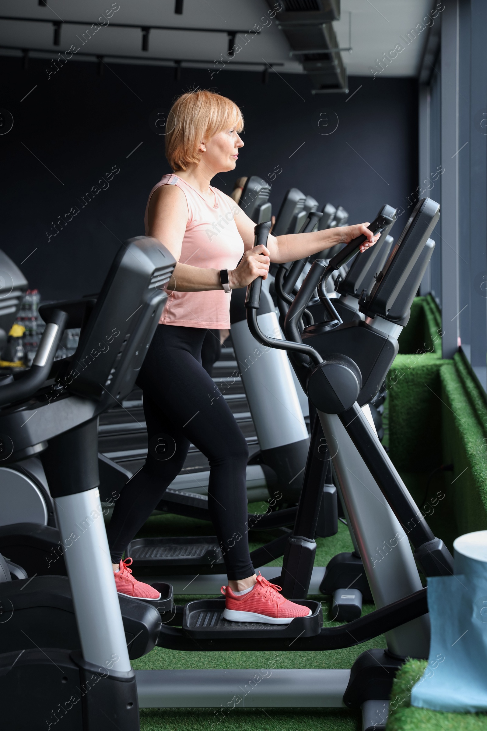 Senior woman training on elliptical machine in gym Photo of Senior woman training on elliptical machine in gym
