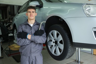 Photo of Professional mechanic with wrench near lifted car in garage