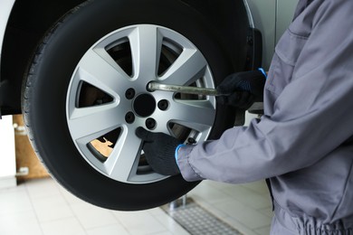 Photo of Mechanic changing tire at car service, closeup