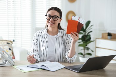 Photo of Travel agent with passports and tickets at wooden table in office