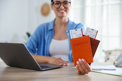 Photo of Travel agent with passports and tickets at wooden table in office, selective focus