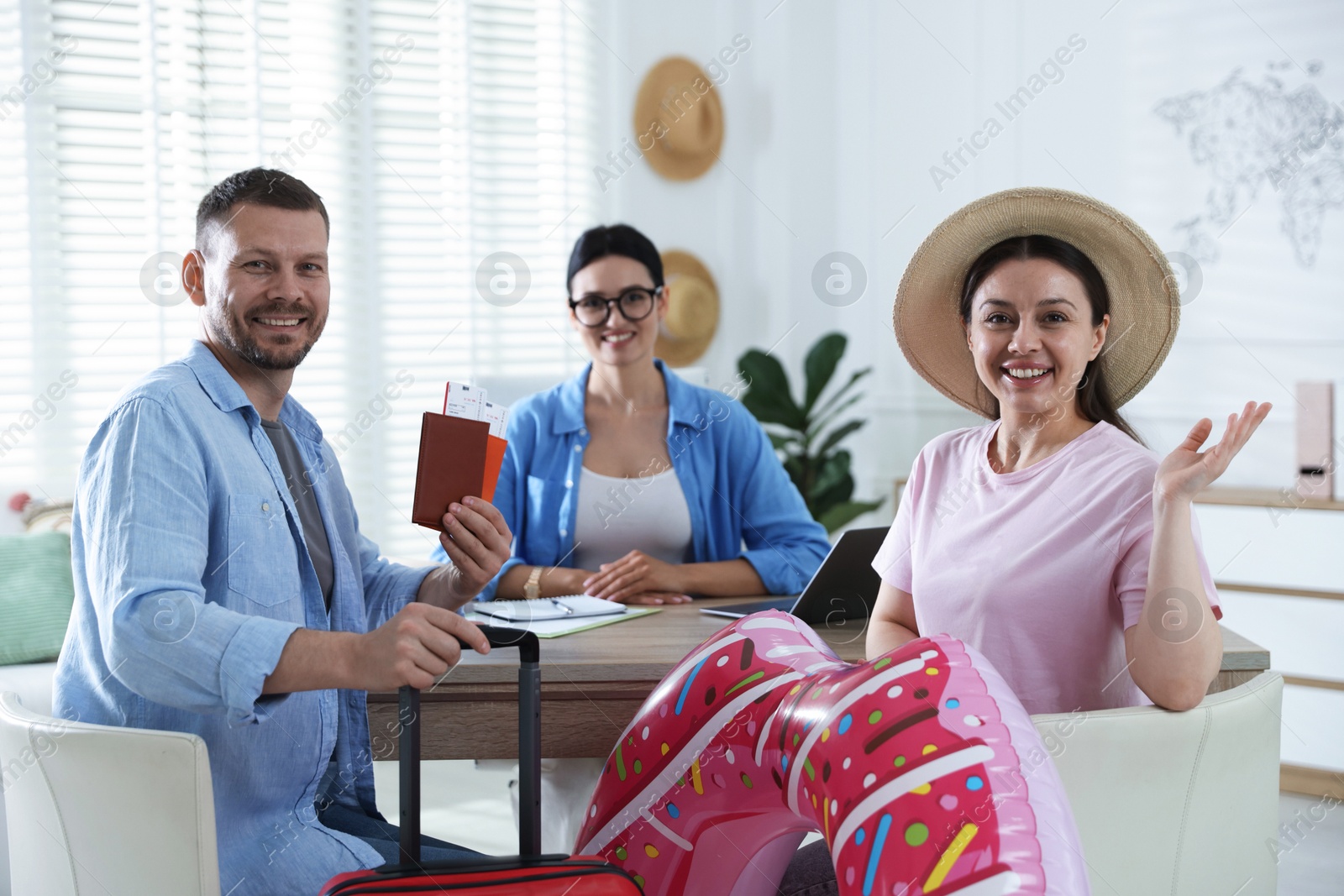 Happy couple planning vacation with travel agent at wooden table in office, selective focus Photo of Happy couple planning vacation with travel agent at wooden table in office, selective focus