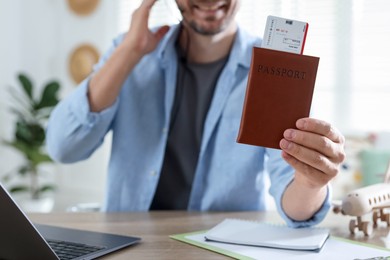 Photo of Travel agent with passport and ticket at wooden table in office, closeup