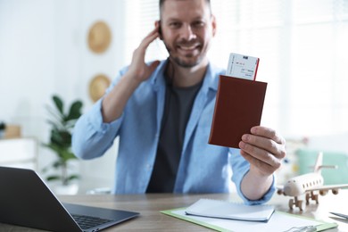 Photo of Travel agent with passport and ticket at wooden table in office, selective focus