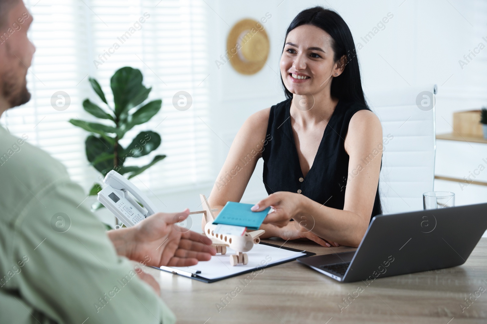 Travel agent giving passport with ticket to man at wooden table in office Photo of Travel agent giving passport with ticket to man at wooden table in office