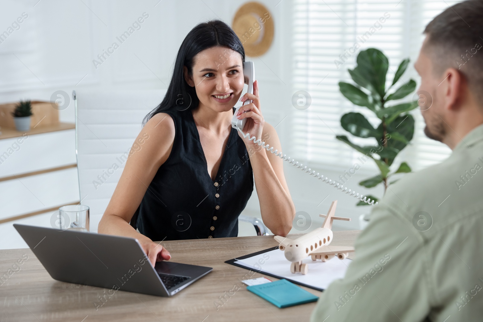 Man planning vacation with travel agent at wooden table in office Photo of Man planning vacation with travel agent at wooden table in office