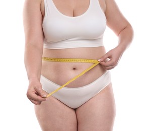 Photo of Weight loss. Plus size woman measuring waist with tape on white background, closeup