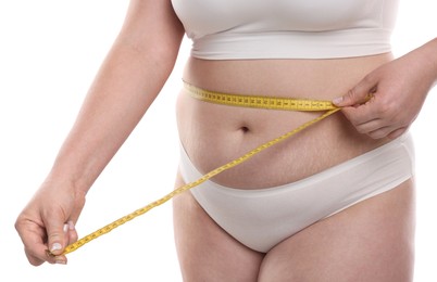 Photo of Weight loss. Plus size woman measuring waist with tape on white background, closeup