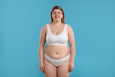 Photo of Weight loss. Plus size woman in underwear on light blue background