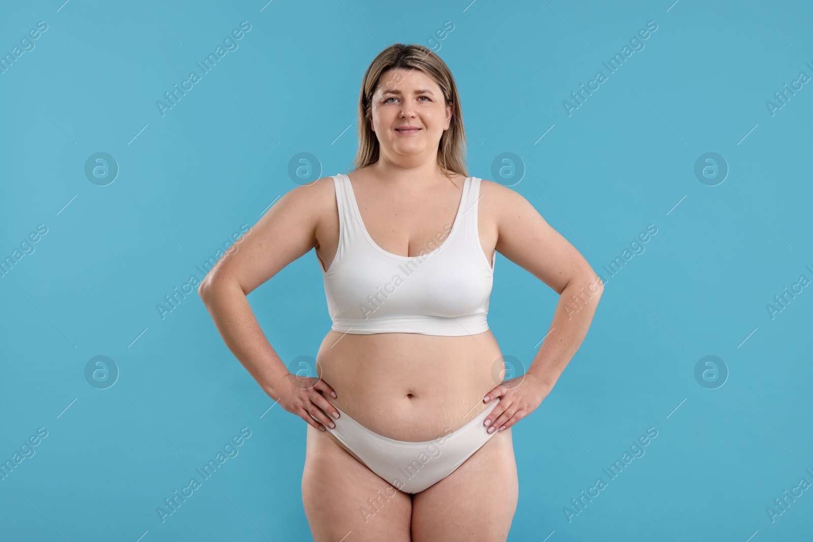 Weight loss. Plus size woman in underwear on light blue background Photo of Weight loss. Plus size woman in underwear on light blue background