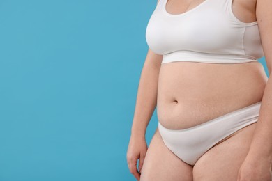 Photo of Weight loss. Plus size woman in underwear on light blue background, closeup. Space for text