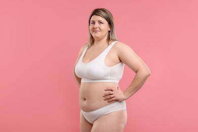 Photo of Weight loss. Plus size woman in underwear on pink background