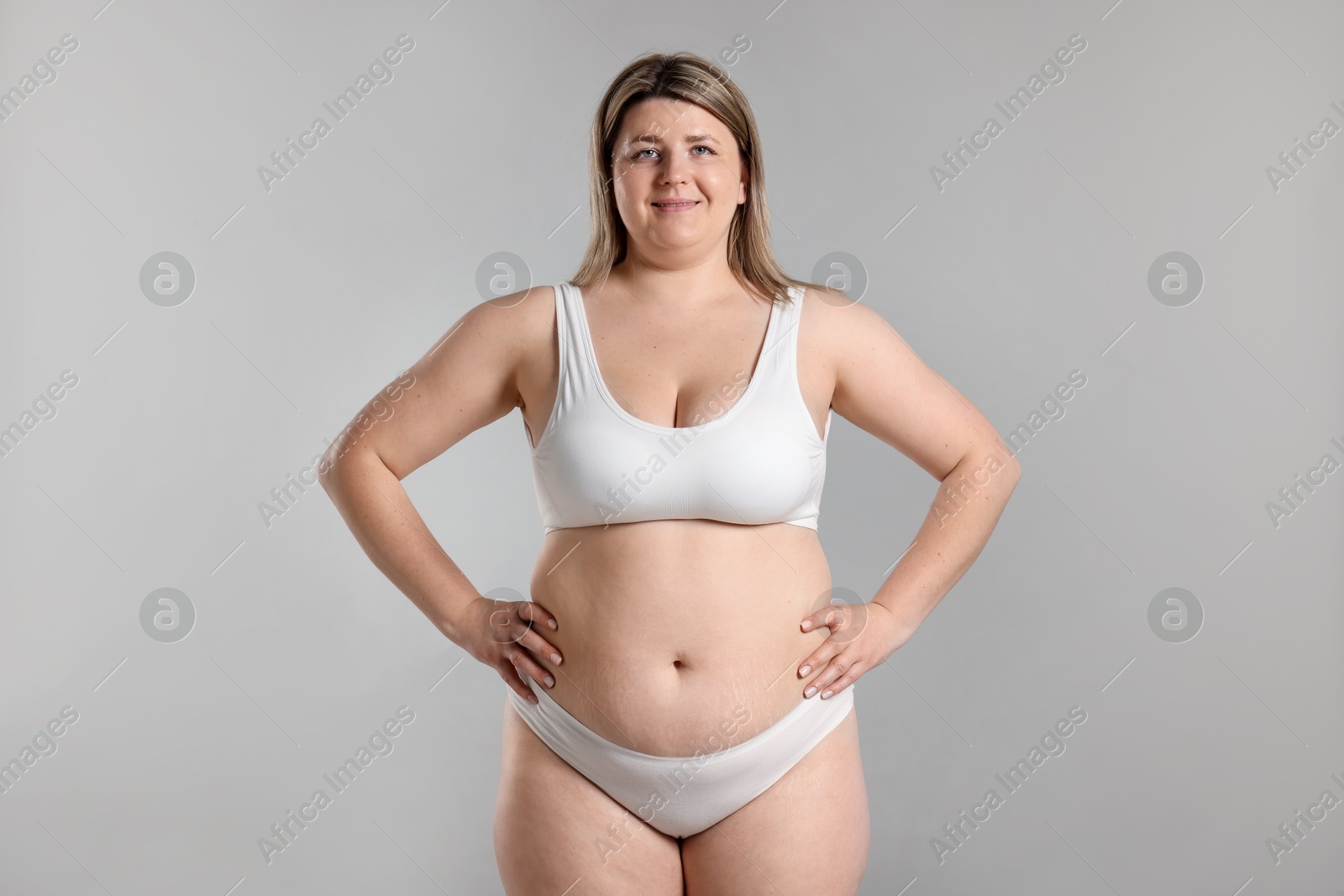 Weight loss. Plus size woman in underwear on gray background Photo of Weight loss. Plus size woman in underwear on gray background