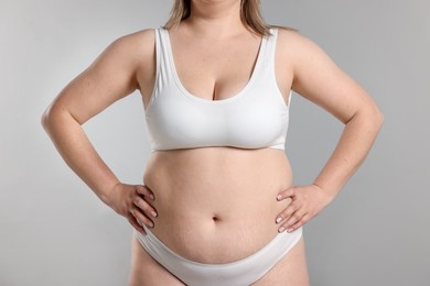 Photo of Weight loss. Plus size woman in underwear on gray background, closeup
