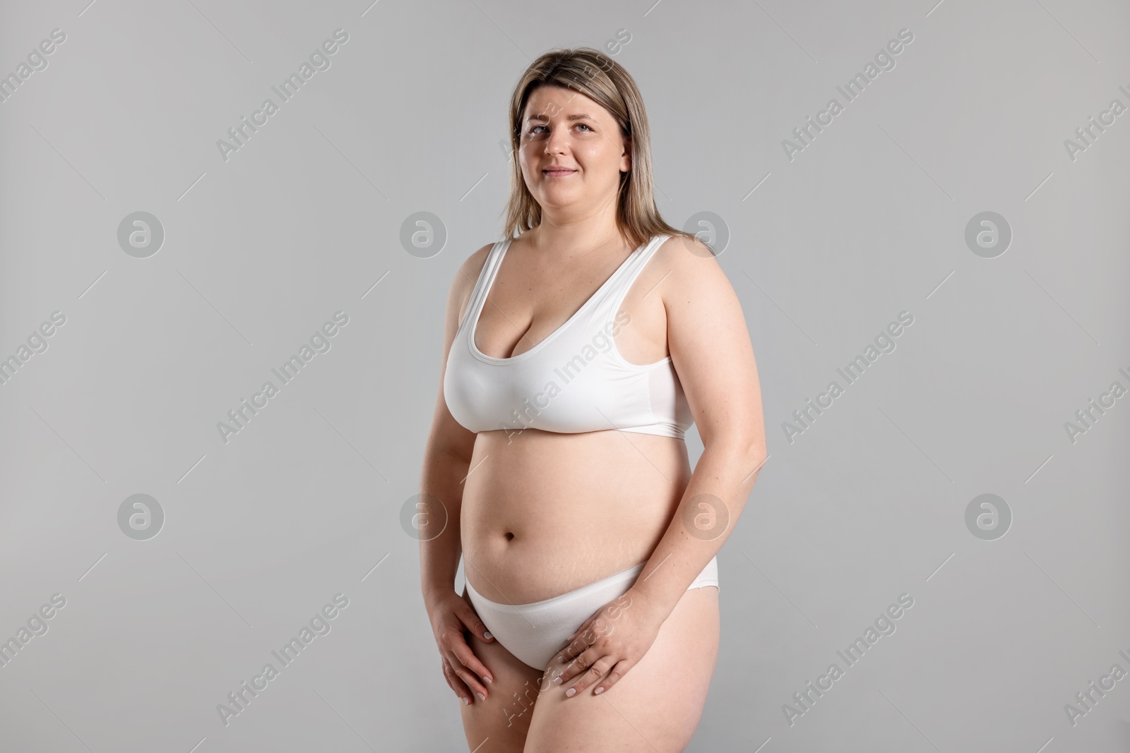 Weight loss. Plus size woman in underwear on gray background Photo of Weight loss. Plus size woman in underwear on gray background