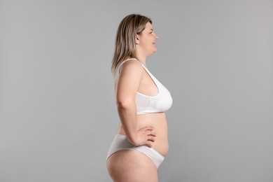 Photo of Weight loss. Plus size woman in underwear on gray background