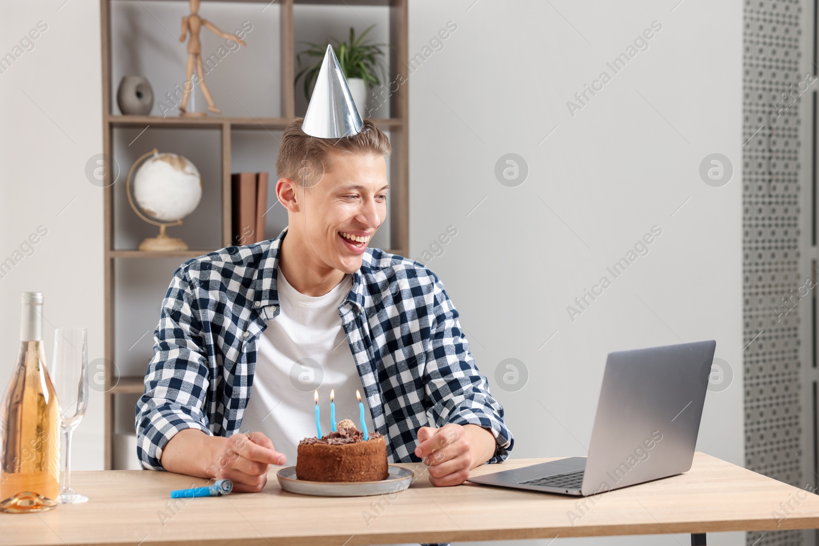 Birthday celebration. Man with cake and sparkling wine having video call via laptop at desk indoors Photo of Birthday celebration. Man with cake and sparkling wine having video call via laptop at desk indoors