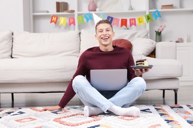 Photo of Man with piece of cake celebrating his birthday and having video call via laptop at home