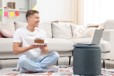 Photo of Man with cake celebrating his birthday and having video call via laptop at home