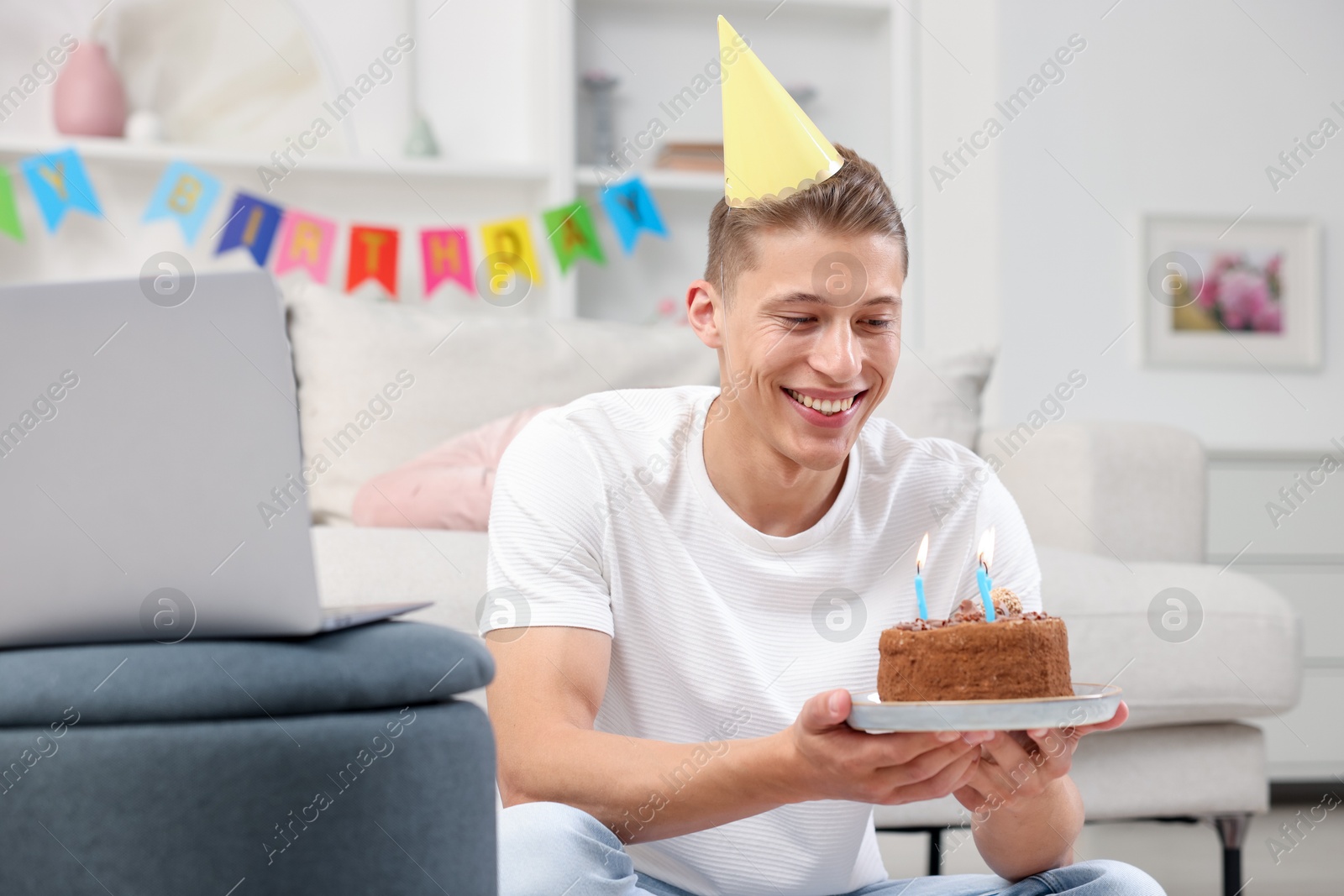 Man with cake celebrating his birthday and having video call via laptop at home Photo of Man with cake celebrating his birthday and having video call via laptop at home